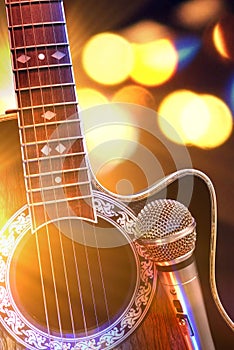 Acoustic guitar and microphone with lights in the background
