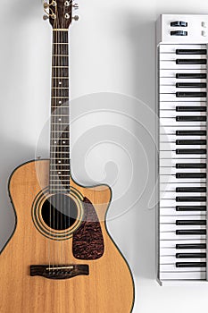 Acoustic guitar and musical keys on a white background, flat lay.