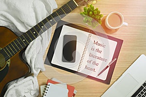 Acoustic Guitar, Notebook and Multiple Items with Musical Quote