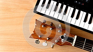 Acoustic guitar and piano keys on a wooden background