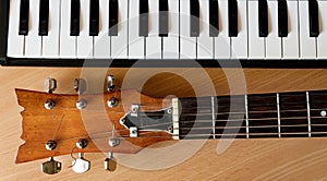 Acoustic guitar and piano keys on a wooden background photo