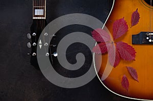 Acoustic guitar and red autumn leaves on dark brown background