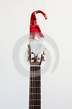 acoustic guitar with red Santa hat. Christmas song music concept on white background