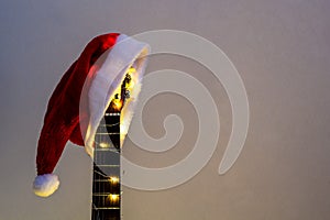 Acoustic Guitar with red Santa hat and light garland. Christmas music song concept with copyspace