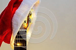 Acoustic Guitar with red Santa hat and light garland. Christmas music song concept with copyspace