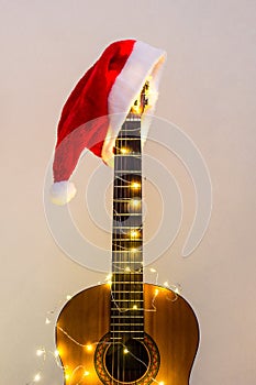 Acoustic Guitar with red Santa hat and light garland. Christmas music song concept with copyspace