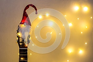 Acoustic Guitar with red Santa hat and light garland. Christmas music song concept with copyspace