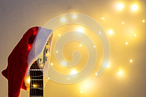 Acoustic Guitar with red Santa hat and light garland. Christmas music song concept with copyspace