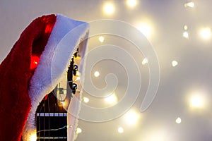 Acoustic Guitar with red Santa hat and light garland. Christmas music song concept with copyspace