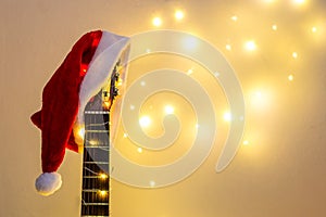 Acoustic Guitar with red Santa hat and light garland. Christmas music song concept with copyspace