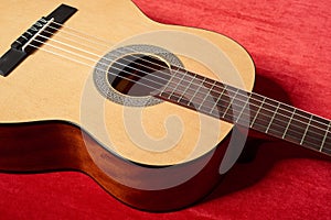 Acoustic guitar on red velvet fabric, closeup object