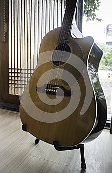 Acoustic guitar resting against mirror background