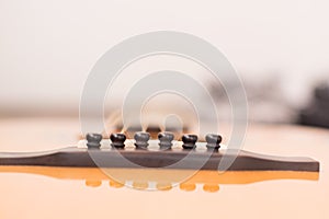 Acoustic guitar resting against a wooden background with copy sp