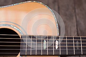 Acoustic guitar resting against a wooden background with copy sp