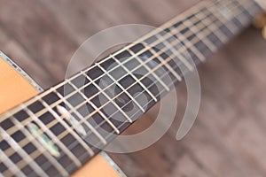 Acoustic guitar resting against a wooden background with copy sp