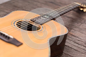 Acoustic guitar resting against a wooden background with copy sp