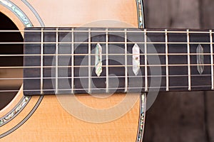 Acoustic guitar resting against a wooden background with copy sp