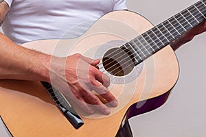 Acoustic guitar resting on a white background with copy space. a person`s hand holding it