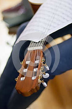 Acoustic guitar's fretboard head and musical scores on a fretboa