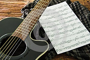Acoustic guitar and sheet musical notes on the table.