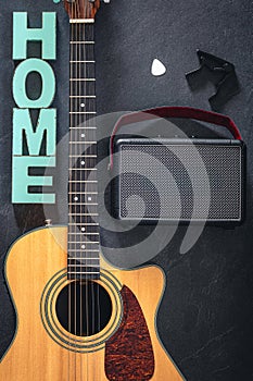 Acoustic guitar, speaker and word Home on a black background, top view.