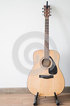 Acoustic guitar stands on the stand in the apartment