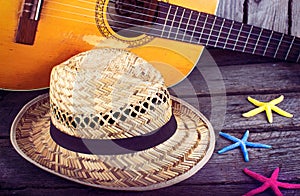 Acoustic guitar star hat and starfish on a grunge wood background