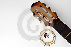 Acoustic guitar strings and pick on white background