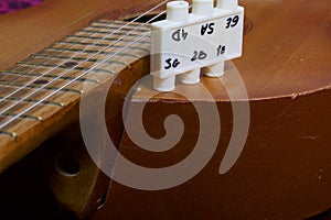 Acoustic guitar and tuning fork to adjust it. On a dark background.