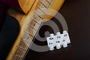 Acoustic guitar and tuning fork to adjust it. On a dark background.