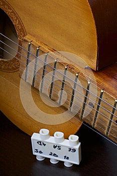 Acoustic guitar and tuning fork to adjust it. On a dark background.