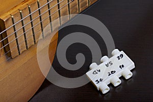 Acoustic guitar and tuning fork to adjust it. On a dark background.