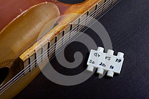 Acoustic guitar and tuning fork to adjust it. On a dark background.