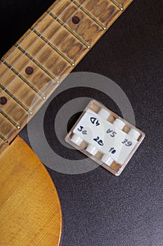 Acoustic guitar and tuning fork to adjust it. On a dark background.