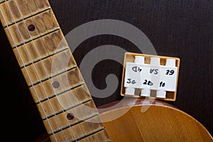 Acoustic guitar and tuning fork to adjust it. On a dark background.