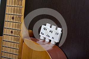 Acoustic guitar and tuning fork to adjust it. On a dark background.