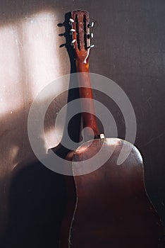 Acoustic guitar at a wall, grunge background.