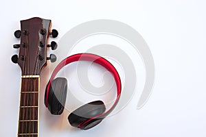 Acoustic guitar on a white background and the headphones are placed on the side. Concept of leisure and music.