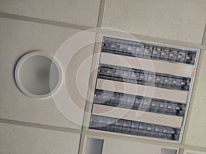 Acoustic panel and light fixtures in t-bar grid of suspended ceiling