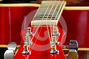 Acoustic red guitar lies on the table in the background with a copy of the hand space, playing acoustic guitar, close-up