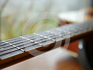 Acoustic wood guitar close up on wooden background with fretboard, strings, and tuners for music blogs, musician social media.