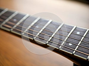 Acoustic wood guitar close up on wooden background with fretboard, strings, and tuners for music blogs, website banners.