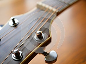 Acoustic wood guitar close up on wooden background with fretboard, strings, and tuners for music blogs, website banners.