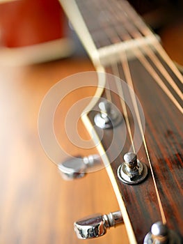 Acoustic wood guitar close up on wooden background with fretboard, strings, and tuners for music blogs, website banners.