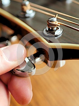 Acoustic wood guitar close up on wooden background with fretboard, strings, and tuners for music blogs, website banners.