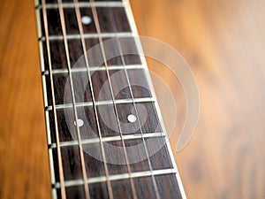 Acoustic wood guitar close up on wooden background with fretboard, strings, and tuners for music blogs, website banners.