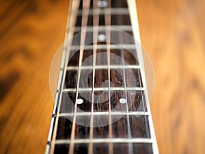 Acoustic wood guitar close up on wooden background with fretboard, strings, and tuners for music blogs, website banners.