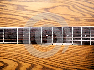 Acoustic wood guitar close up on wooden background with fretboard, strings, and tuners for music blogs, website banners.