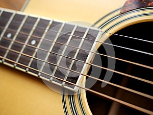 Acoustic wood guitar close up on wooden background with fretboard, strings, and tuners for music blogs, website banners.