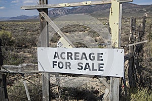 Acreage for Sale Sign Along Fence with Mountain Backdrop in Desert